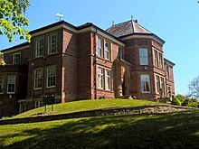 A large red brick house on a grassy mound