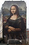 Farbfotografie von der Hauswand eines viergeschossigen Gebäudes, worauf Mona Lisa mit Farben übertragen wurde.