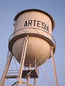 Water tower with Artesia written across it. Picture is taken from below and shows only a cloudless sky in the background