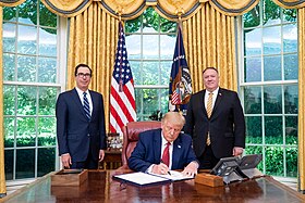 Donald Trump signing the order with Steven Mnuchin and Mike Pence