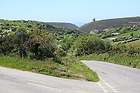 Road Junction. One road leads down into the steep valley which reaches the sea at Porthtowan. On the hillside in the distance is a lone engine house from an old mine.