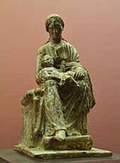 Photograph of a terracotta figurine of a young woman, seated, facing right