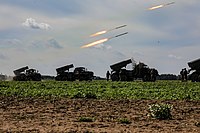 Military vehicles firing rockets in a field