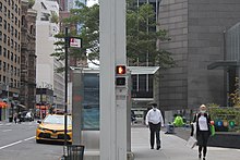 Custom pylon at the northeast corner of Lexington Avenue and 53rd Street. The pylon is square and painted gray. There are pedestrian traffic signals embedded into the sides of the pylon.