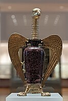 A gold eagle metalwork surrounding a vase