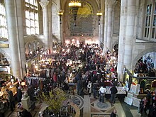 View of banking room in 2010. There is a crowd of people attending a fair in the middle of the banking room. Large windows are visible to the left.