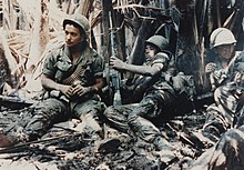 Three American soldiers lying in mud in Vietnam in 1968