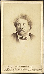 Photograph of Alexandre Dumas wearing a bowtie and looking slightly off camera. A typed caption at the bottom of the image reads "Ch. Reutlinger Phot." and an annotation in pencil denotes the name of the subject.