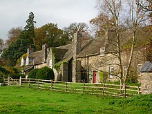 A row of stone-wall cottages on the Dinefwr Estate next to a field