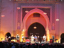 Concert stage with a band performing and the gate of Bab Dekkakin in the background