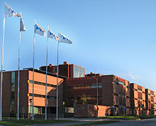 a large building with flagpoles in-front of it to its west