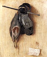 A dead bird and two leather gloves hanging on a wall