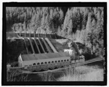 B&W image of powerhouse in the foreground with the back sided of the dam in the foreground.