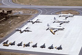 An aerial view of Royal Australian Air Force (RAAF) fighters, Royal New Zealand Air Force (RNZAF) and United States Navy (USN) patrol aircraft (bottom to top) parked on a ramp during exercise Sandgroper 1982. Visible are seven Dassault Mirage IIIO and one Mirage IIID of No. 77 Squadron RAAF, two Lockheed P-3C Orion aircraft of No. 10 Squadron RAAF, one Lockheed P-3B Orion of No. 5 Squadron RNZAF, and two P-3B (BuNos 152733 and 153418) of Patrol Squadron VP-1 Screaming Eagles, USN.