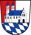 Stadt Wertingen Über Schildfuß mit den bayerischen Rauten gespalten von Rot und Silber, überdeckt mit einer auf der Teilungslinie stehenden silbernen zweitürmigen, blaubedachten Kirche in perspektivischer Seitenansicht.