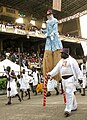 A performer on stilts as part of the Eyo Agere Molokun procession parading in the TBS.
