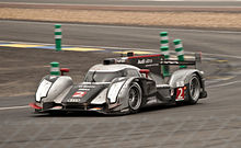 A photograph of a silver and black Audi R18 TDI LMP1 sports prototype