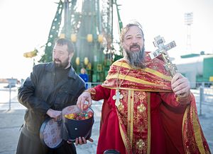 A priest distributing blessed Easter eggs after blessing the Soyuz rocket