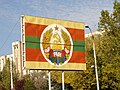 A road signboard with civil flag of Transnistria that superimposed with simplified version of the national emblem