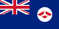 A British Blue Ensign (a blue flag with the Union Jack placed at the top left corner) charged with a white disc containing the badge of the Straits Settlements (red diamond with an inverted white Y; inside that inverted Y is three crowns.