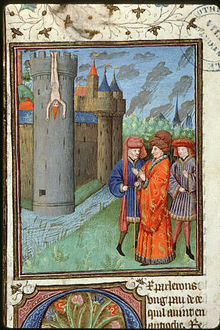 A naked man is hung out from the top of a tower while three men are talking at the tower