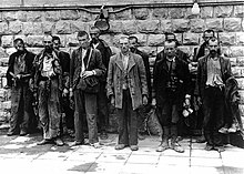 Disheveled men standing against a wall