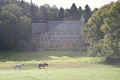 A photograph of St Margaret's Church, surrounded by trees, with a grass field in the foreground