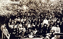 Large group of men in front of trees
