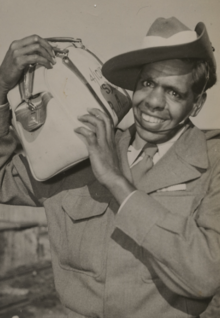a black and white photograph of a smiling Aboriginal male wearing Australian Army uniform and slouch hat