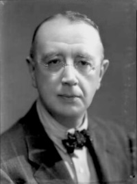 middle-aged white man, clean shaven, bespectacled, thinning hair looking towards the camera
