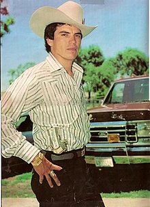 Chalino Sánchez poses with a holstered M1911 in front of a truck