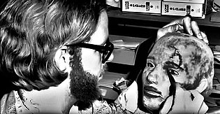 Robert Burns applying paint to a latex mask mold.