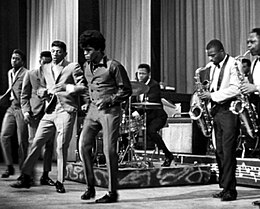 The Famous Flames (L–R: Bobby Bennett, Lloyd Stallworth, Bobby Byrd and James Brown) performing at the Apollo Theater in New York, 1964. Brown's band is on the right.