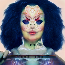 Björk is in the middle of the album cover. Björk is holding a flute. Björk have a blue hair, a two hole in the middle of throat. In her neck there is a embryo looking bird. in her face a pearl lies in her face. she have a blush and a liptick but in the upper lips it is messy. Her eyes is blue and her undereyes is blue. Her forehead a pearl is in the middle surrounded by a two ears looking that lines her eyebrows up to her nose and her skin is mixed with a Blue, Green, Peach color.