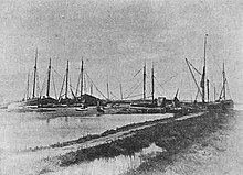 monochrome photograph of seaside quay with many fishing boats tied up