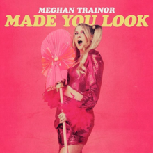 A blonde woman in a pink dress holding a prop. The text "Meghan Trainor Made You Look" stands above her.