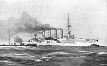 A large, light gray warship steaming in choppy seas with a small, black warship steaming close by.