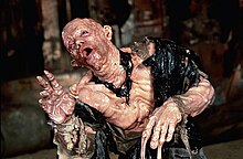A behind-the-scenes photograph of actor Paul McCrane in a prosthetic costume depicting melting skin