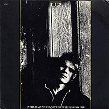 Black and white image of a man leaning against glass. "U2" Text is written in the top-middle, and the title of the song is written at the bottom.