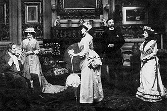 stage scene in 1885 costumes with three women and two men: a young woman earnestly addresses her stern father