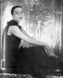 slim young woman in evening dress, seated, looking towards the camera