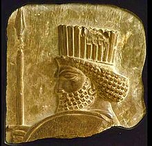 A stone panel with the head of a bearded man seen in profile, the top of his shield, and an upright spear tip on the left