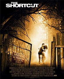 A couple of teens run inside the forest, past a gate with a warning sign.