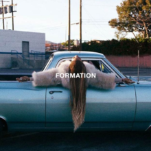 Cover art for "Formation": Beyoncé in a blue pickup truck, her arms outstretched and upper half sticking out the window