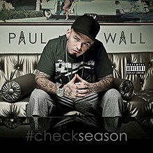 The cover features Paul Wall sitting on a black sofa, wearing a black t-shirt and baseball cap, and grey jeans. Below him is a black table that features the album's title, with "#" and "check" colored in black and "season" colored in white. Wall's name is behind him, colored in black and the "A's" are written like towers.
