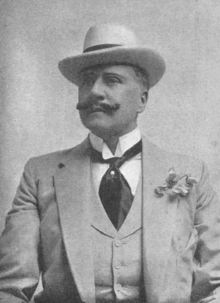 dandyish middle-aged white man, with dapper moustache in elegant summer suit