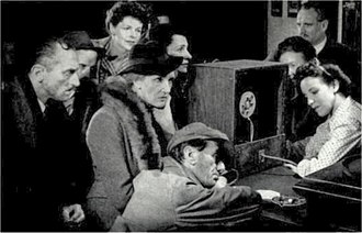 group of people listening to an old-fashioned radio set