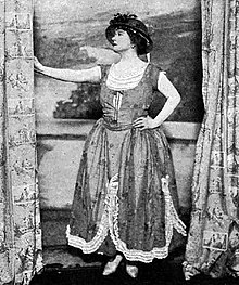 middle aged white woman, extravagantly dressed, striking a theatrical pose