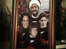 A framed Christmas family portrait. The father, mother, and two sons are wearing identical sweaters.