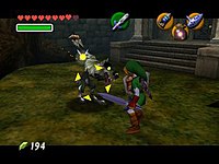 The adult version of Link, armed with a sword and shield and wearing a green tunic, is fighting a bipedal wolf in front of the Forest Temple. Link's fairy companion, Navi, has turned yellow and hovers above the creature, which is now surrounded by yellow crosshair-like arrows.